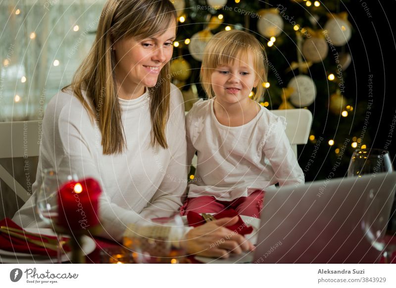 Eine glückliche Familie mit einem Kind feiert Weihnachten mit ihren Freunden per Videoanruf per Webcam. Die Familie begrüßt ihre Verwandten am Heiligabend online. Neue normale virtuelle Veranstaltung