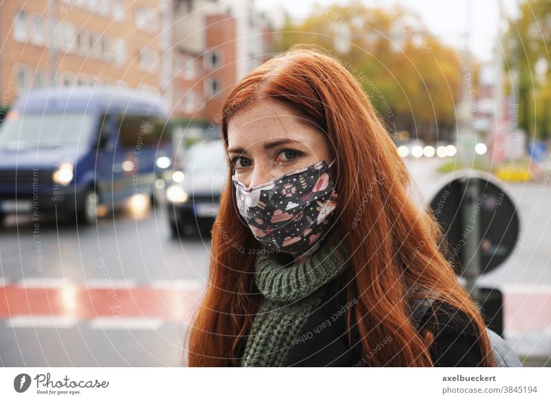 junge Frau, die im Stadtverkehr eine Alltagsmaske trägt Mundschutz Gesichtsmaske Straße Verkehr Winter echte Menschen Gemeinschaftsmaske Stoff Lifestyle