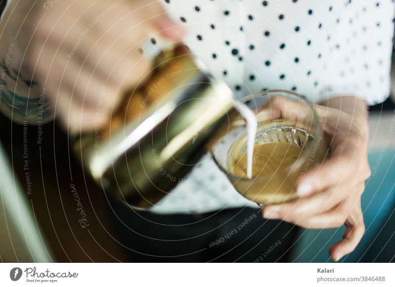 Barista macht ein Glas Milchkaffee mit Latte Art in der Hand milchschaum gießen café au lait Espresso Latte Macchiato Kaffee Café Frau genießen trinken
