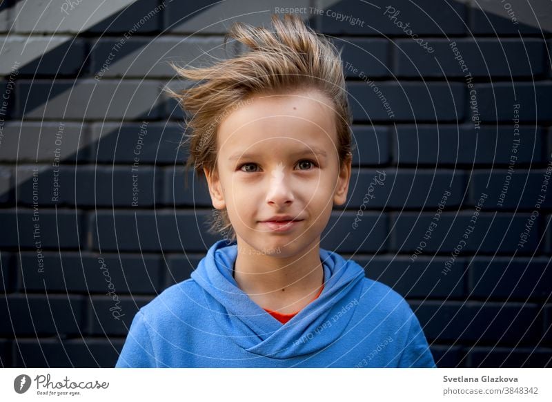 Lustiges Porträt eines blonden, kaukasischen Jungen, dessen Haar sich hebt und im Wind fliegt. Schaut in die Kamera lustig Kind Kindheit Hintergrund Glück