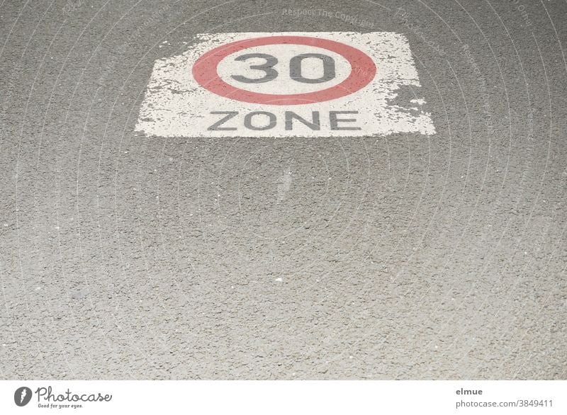 Auf der asphaltierten Straße ist ein Geschwindigkeitsbegrenzungsschild "Zone 30" aufgemalt / verkehrsberuhigte Zone / langsam fahren / Tempo 30 Verkehrsschild