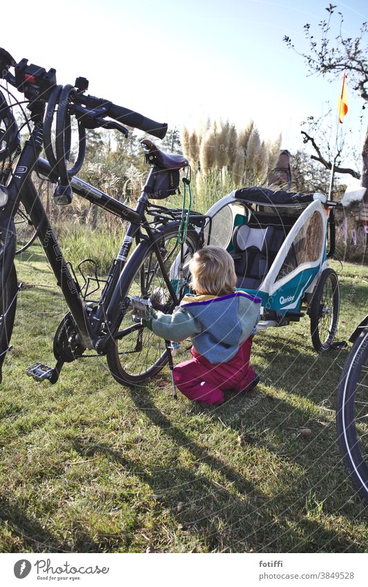 Kleinkind begeistert sich für Fahrräder Fahrrad Fahrradanhänger Neugier gucken anfassen anlecken quietschvergnügt Garten Rasen Kleingarten schrebergarten sommer