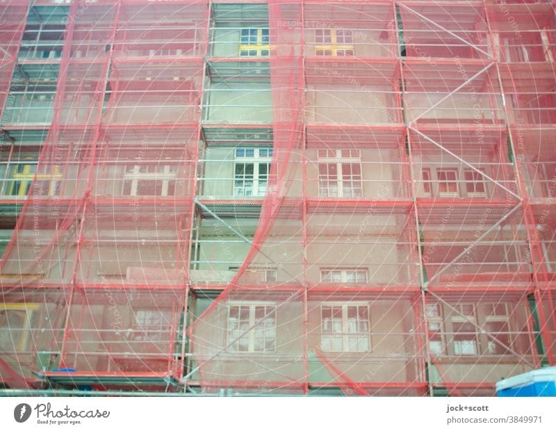 Grüner wohnen, Baustelle mit rötlichen Baugerüst Fassade Abdeckung Schutz authentisch Strukturen & Formen Sicherheit Sanieren Renovieren Haus Fenster