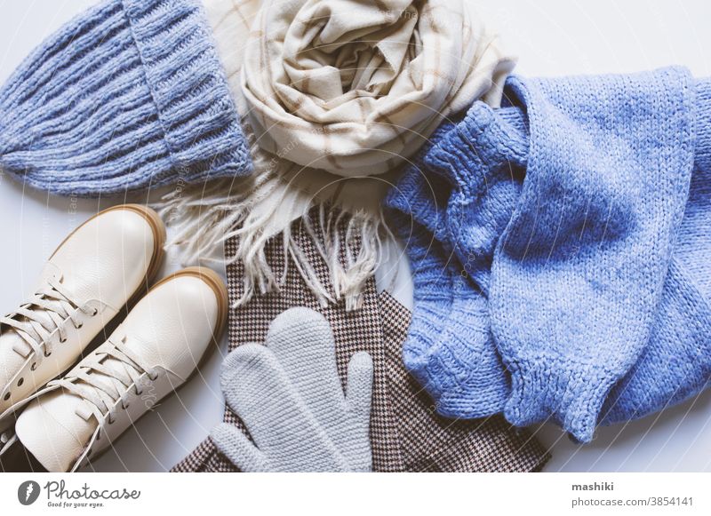 stilvolle, moderne Winter- oder Herbstkleidung für Frauen von oben betrachtet. Trendige Schuhe, Pullover und Accessoires in Beige- und Blautönen mit Weihnachtsbeleuchtung und Herbstlaub.