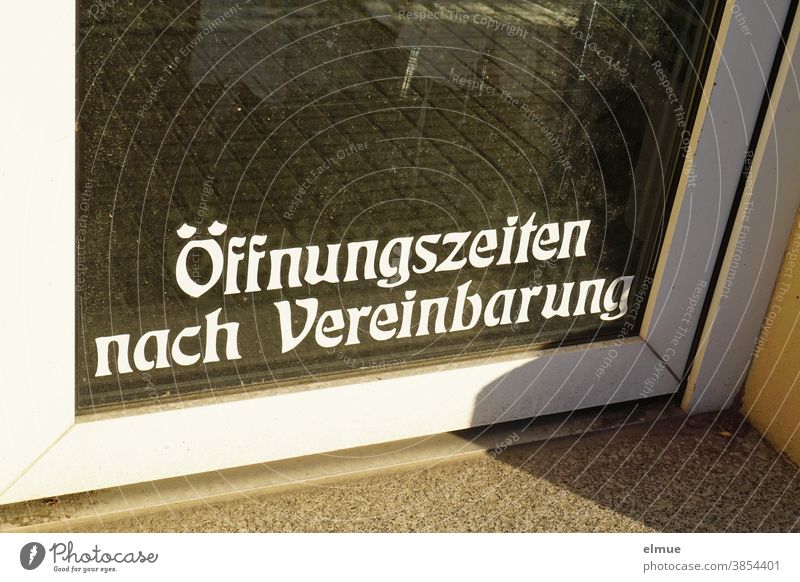 "Öffnungszeiten nach Vereinbarung" steht in weißer Druckschrift im unteren Teil einer Glastür zu einem Geschäft. Ladentür Ausnahmesituation geschlossen