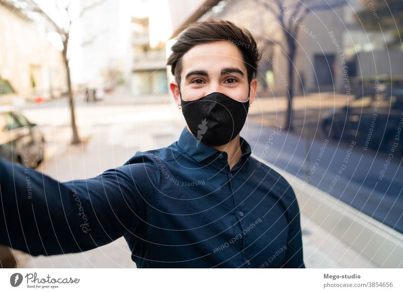 Porträt eines jungen Mannes, der ein Selfie im Freien macht. Gesicht Mundschutz covid-19 außerhalb normal neu Lifestyle Selfie machen Leben lässig Stil tragend