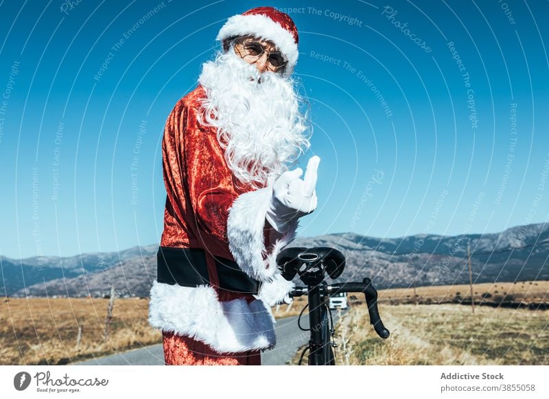 Unhöflicher Weihnachtsmann zeigt Mittelfinger ficken unverschämt gestikulieren Fahrrad Straße Weihnachtsmütze auflehnen expressiv männlich stehen ländlich