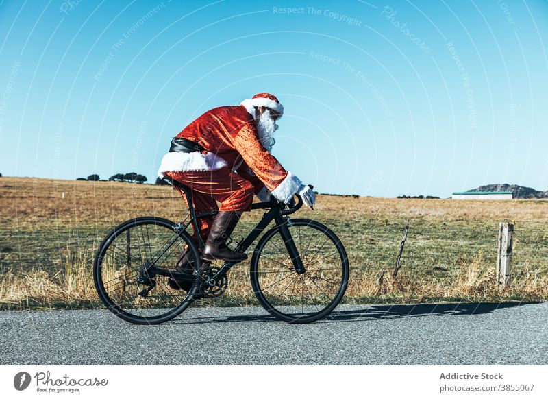 Weihnachtsmann auf dem Fahrrad entlang der Bergstraße Mitfahrgelegenheit Straße leer Berge u. Gebirge Tracht rot Farbe männlich modern Reise Freiheit