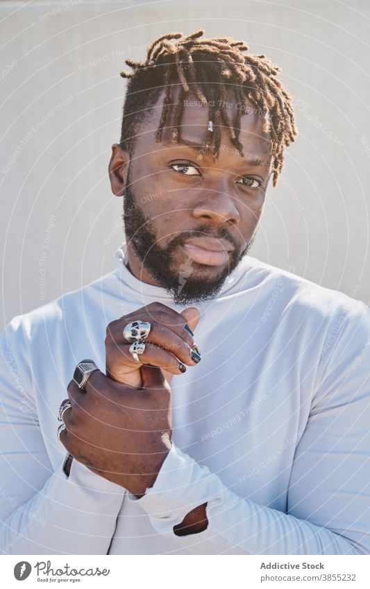 Stilvoller schwarzer Mann mit ungewöhnlichem Aussehen Rastalocken Vorschein Maniküre ausgefallen Frisur Ring Hipster Porträt männlich ethnisch Afroamerikaner