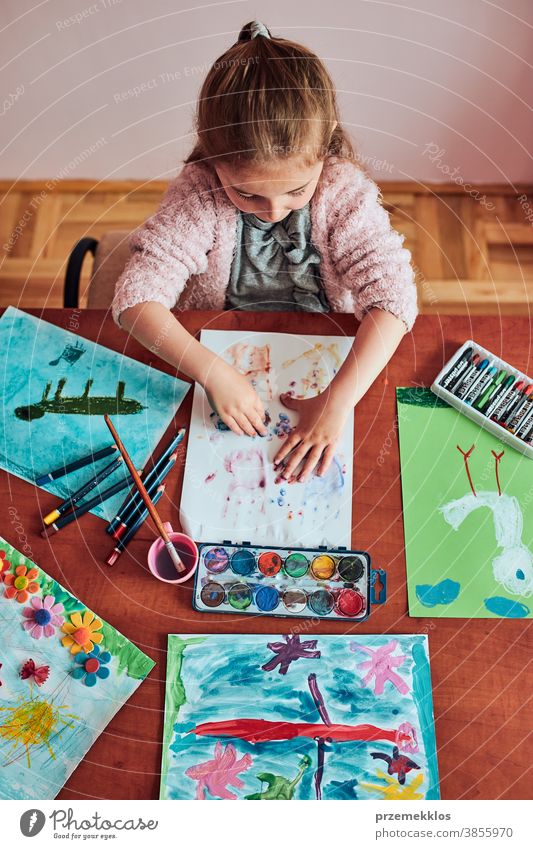 Kleines Mädchen im Vorschulalter, das mit bunten Farben und Buntstiften ein Bild malt Kind Malerei Farbstoff Bildung farbenfroh Kunst heimwärts Papier Kindheit