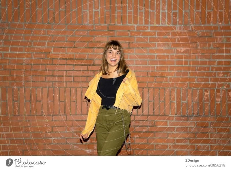 Hübsche junge Frau steht nachts an einer alten Ziegelmauer in der Stadt Stehen attraktiv Lächeln Glück Wand Baustein Freizeitkleidung Person schön Lifestyle