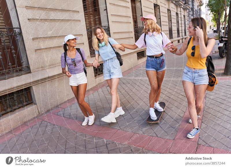Glücklich teen Freundinnen zu Fuß auf der Straße der Stadt Menschengruppe Teenager Spaß haben Zusammensein heiter Skateboard Spaziergang urban