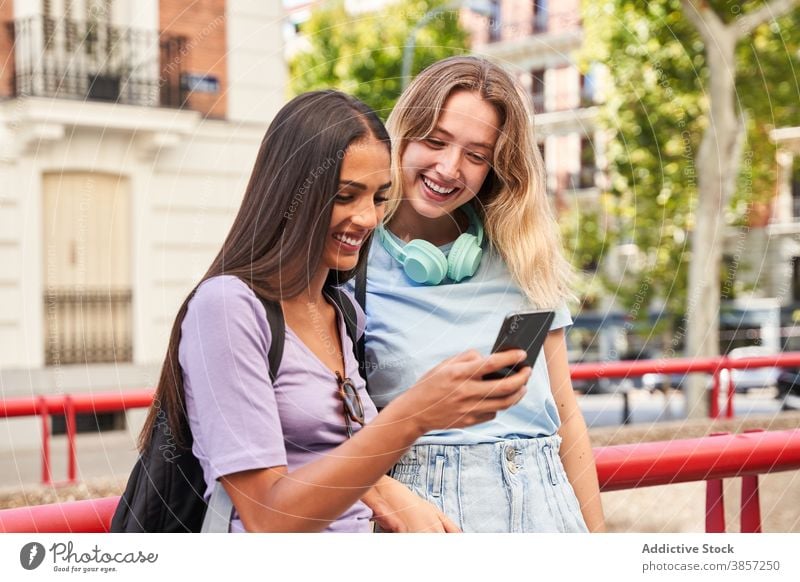 Glückliche junge Frauen mit Smartphone auf der Straße Freundin benutzend Lachen heiter urban Zusammensein zuschauen Mobile Telefon Teenager Inhalt Mädchen