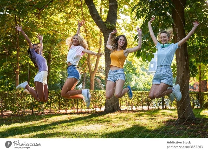 Gruppe von verschiedenen Teenager-Freundinnen springen hoch im Park Spaß haben Sommer Glück heiter Zusammensein Frauen rassenübergreifend multiethnisch