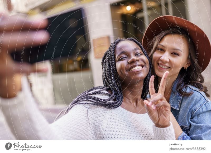 Zwei schöne multiethnische Frauen, die Selbstgefälligkeit und Grimassen schneiden Selfie Smartphone Lifestyle jung Mädchen Lächeln Straße Glück lässig urban