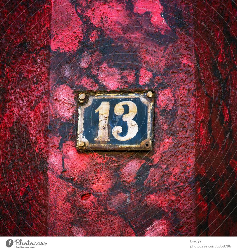 Verwitterte Hausnummer 13 auf rot - schwarzer Hauswand. Zahl 13 verwittert alt Rost Farbe Aberglaube Ziffern & Zahlen Zentralperspektive