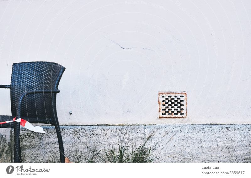Bitte nicht Platz nehmen: ein Stuhl auf der Terrasse steht leer, Gäste dürfen nicht bewirtet werden Flatterband Absperrung schwarz Wand grau geschlossen