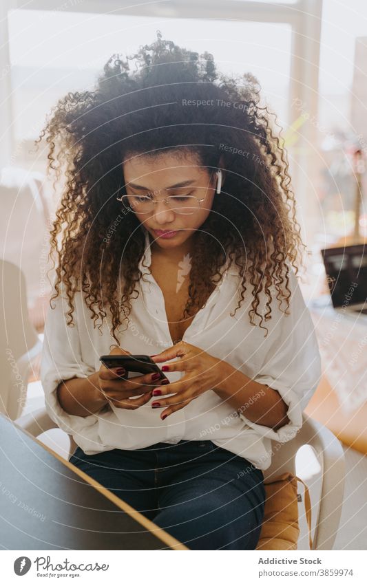 Seriöse schwarze Geschäftsfrau verwendet Smartphone zu Hause Unternehmer beschäftigt freiberuflich abgelegen Arbeit heimwärts Büro online Frau ethnisch