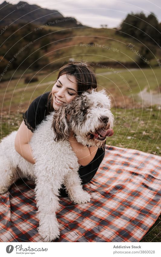 Lächelnde Frau umarmt Hund in der Natur Besitzer kuscheln Freundschaft spanischer Wasserhund Zusammensein Umarmung genießen Decke Wochenende Haustier Tier