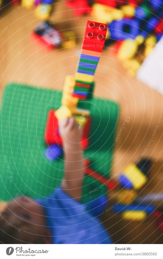 Kind spielt mit Bauklötzen im Kinderzimmer und baut einen Turm Spielzeug spielen Kreativität bauen duplo Spaß Kindheit Freude