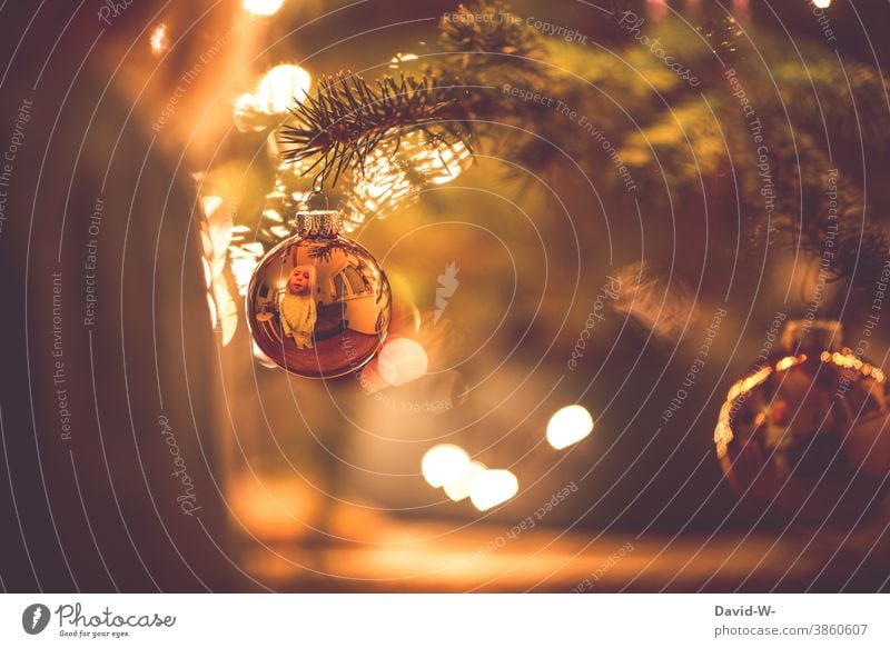 Weihnachten - Kind schaut freudig in eine Christbaumkugel und entdeckt sein Spiegelbild Weihnachten & Advent Weihnachtsbaum spiegeln niedlich Vorfreude wärme