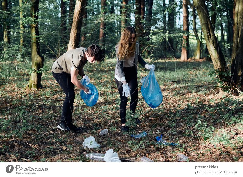 Junger Mann und Frau räumen einen Wald auf. Freiwillige, die Plastikmüll in Säcke sammeln Aktivist Tasche Flasche Pflege Kind Sauberkeit abholen Konzept