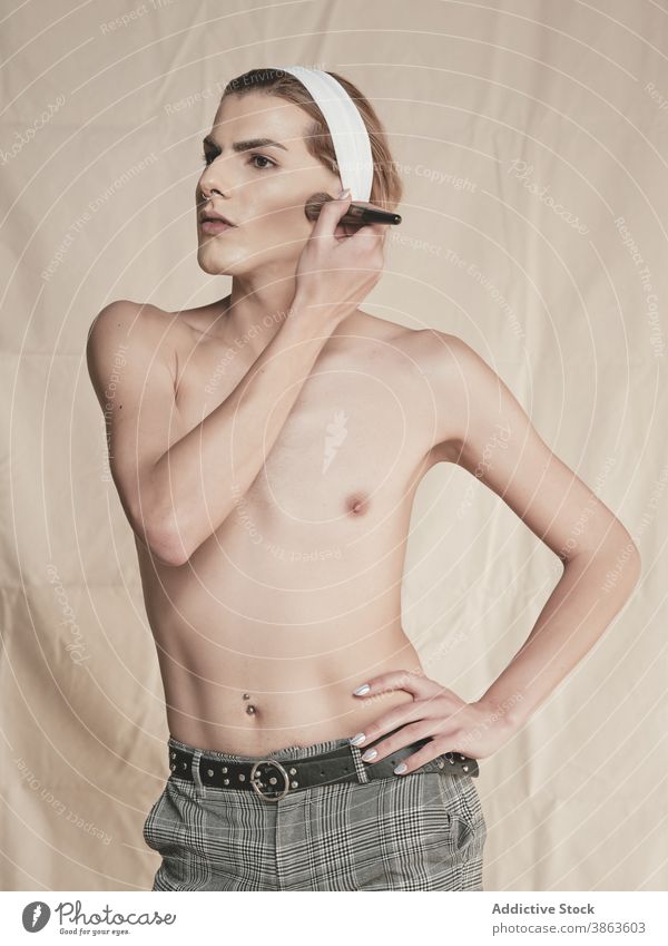 Stilvolle shirtless Kerl Anwendung Make-up Mann androgyn bewerben Vorschein Rouge schlank Hand auf der Taille Transgender männlich jung Model ohne Hemd Wange
