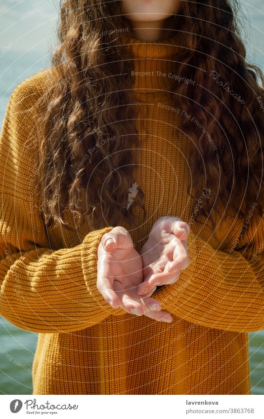 Gesichtsloses Porträt einer Frau am Strand, die ihre Hände nach vorne ausstreckt Pullover Nahaufnahme Handflächen fragen Konzept Halt Geben gesichtslos tragen