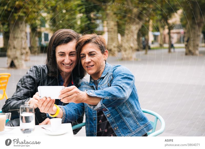 Lesbisches Paar mittleren Alters, das ein Selfie nimmt lesbisch lgbtq schwul mittleres Alter 40 50 Smartphone Selbstportrait Handy Lächeln Homosexualität Frauen