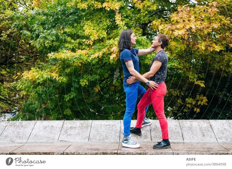 Lesbisches Paar mittleren Alters genießt gemeinsam im Park lesbisch lgbtq schwul mittleres Alter 40 50 umarmend Beteiligung Umarmen Lächeln Homosexualität