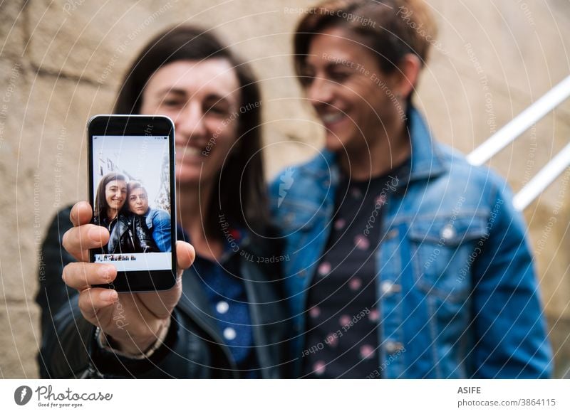 Glückliches lesbisches Pärchen mittleren Alters, das ein Selfie im Smartphone zeigt Paar lgbtq schwul mittleres Alter 40 50 Lachen Selbstportrait Lächeln