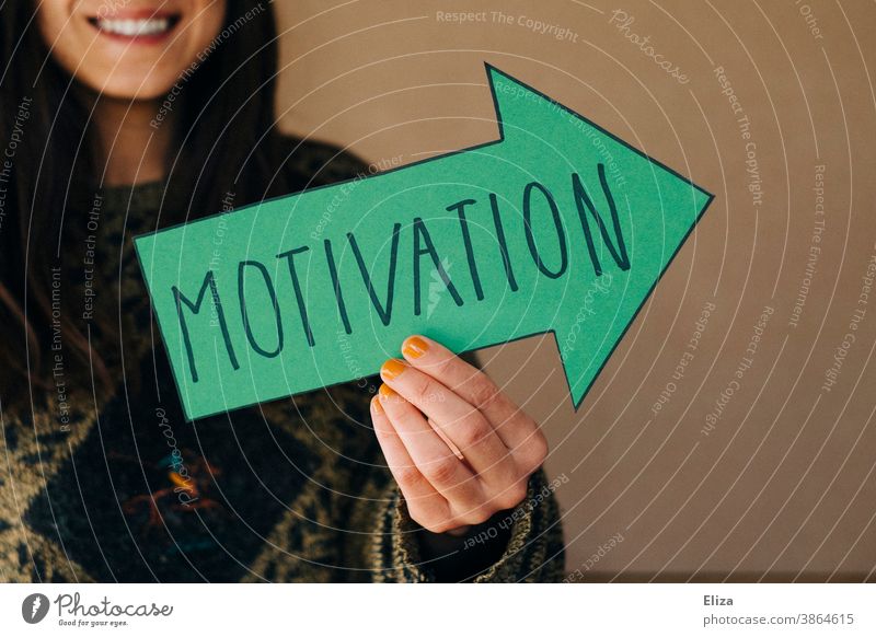 Eine Frau hält einen grünen Pfeil mit der Aufschrift Motivation motivieren Lob Anerkennung Beruf Orientierung Zukunft Karriere Erfolg Ziel Richtung ehrgeizig