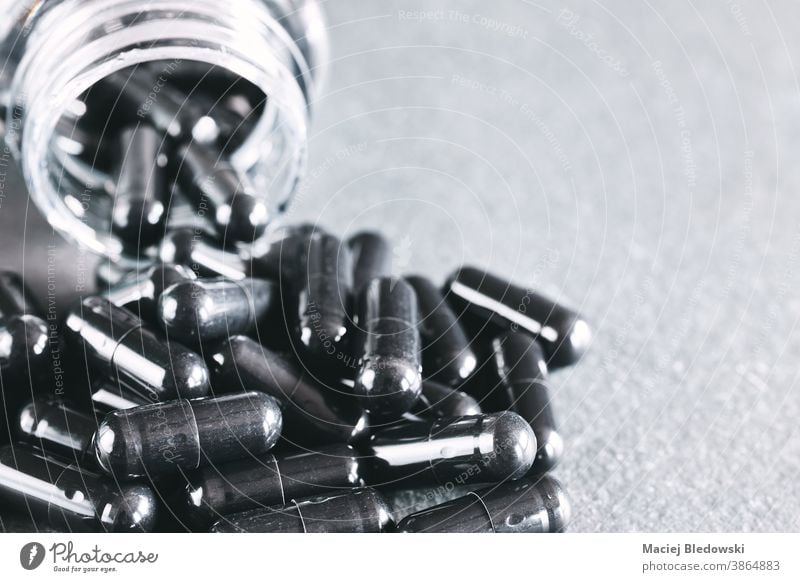 Nahaufnahme von schwarzen Kapseln, die aus dem Behälter ausgelaufen sind. Medikament Medizin Gift Sucht Gefahr Tod Tablette Behandlung medizinisch Apotheke