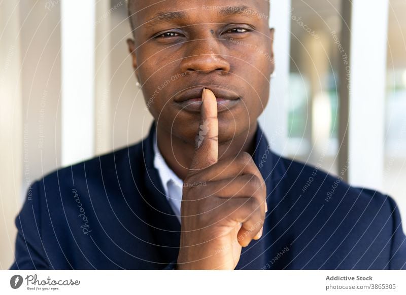 Glücklicher schwarzer Mann schaut in die Kamera Porträt Herstellung gestikulieren Vorschein Stille lässig Outfit Piercing Ohrringe cool männlich ethnisch