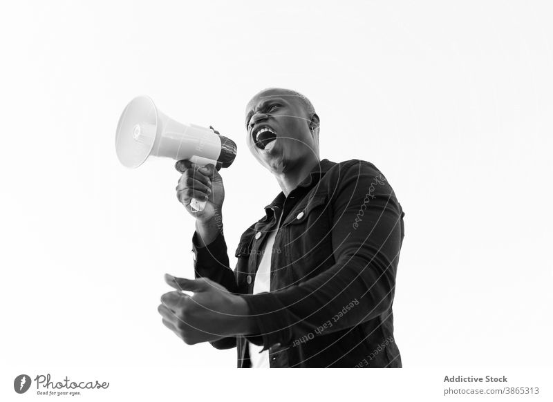 Aufgeregter schwarzer Mann mit Megaphon auf weißem Hintergrund Lautsprecher Schrei Hupe ankündigen verrückt aufgeregt männlich ethnisch Afroamerikaner