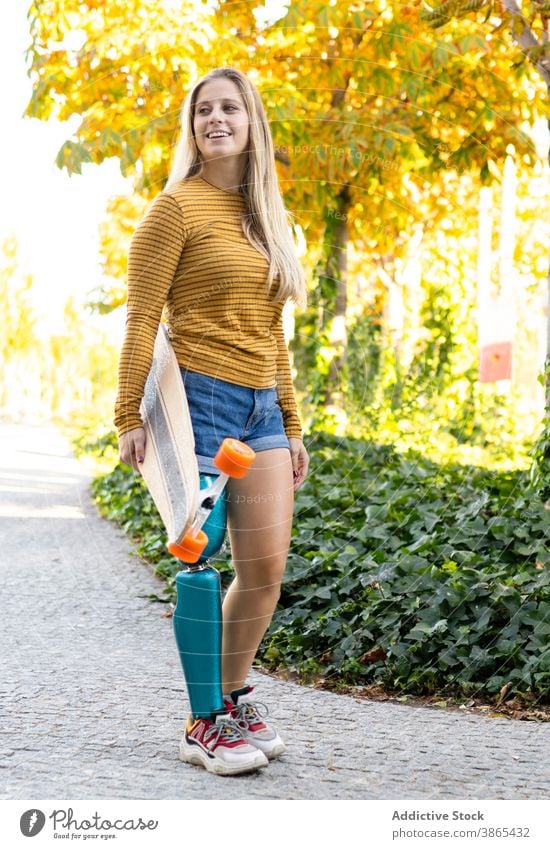 Lächelnde Frau mit Longboard zu Fuß auf der Straße Bein Prothesen Bionik Skater künstliches Glied Spaziergang deaktivieren urban Skateboard Amputierte Stadt