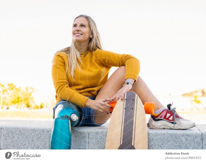 Junge Frau mit Beinprothese und Longboard in der Stadt Prothesen Bionik Skater künstliches Glied sich[Akk] entspannen Großstadt sorgenfrei Amputierte urban