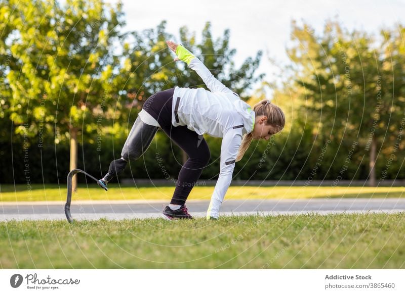 Sportliche Frau mit Beinprothese beim Training im Park explosiv Start Läufer paralympisch Prothesen laufen Sportlerin künstliches Glied Übung Bionik bereit