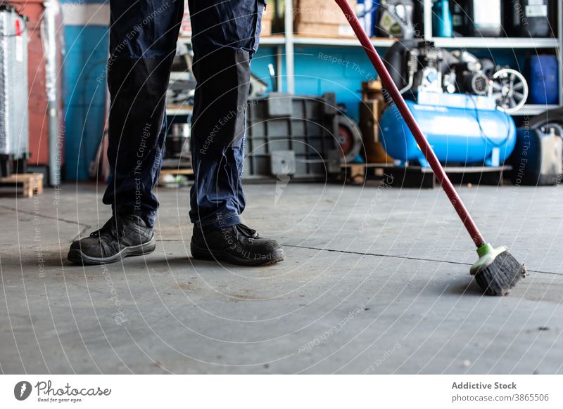 Nicht erkennbarer Mechaniker beim Kehren des Bodens in der Werkstatt Mann Stock Garage Arbeit Besen Sauberkeit Uniform männlich Job professionell Dienst