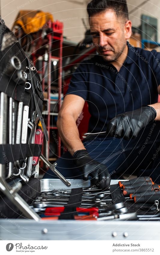 Bild eines Mechanikers, der Bits aus einer Box auswählt Mann Kasten Meissel wählen Garage Arbeit Schraubendreher Werkzeug professionell männlich Techniker Job