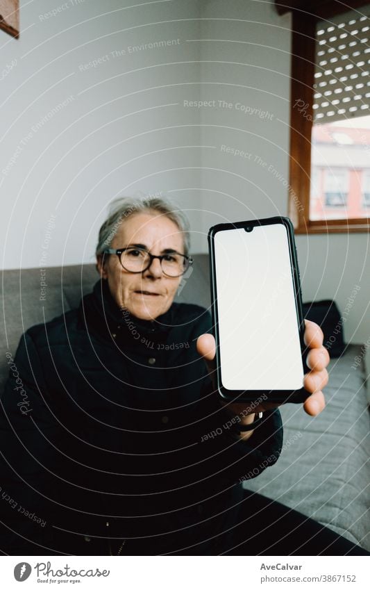 Alte Frau zeigt ein Mobiltelefon mit einem weißen Bildschirm mit Kopierraum Person älter Großmutter copyspace reif Senior Glück in den Ruhestand getreten Anruf