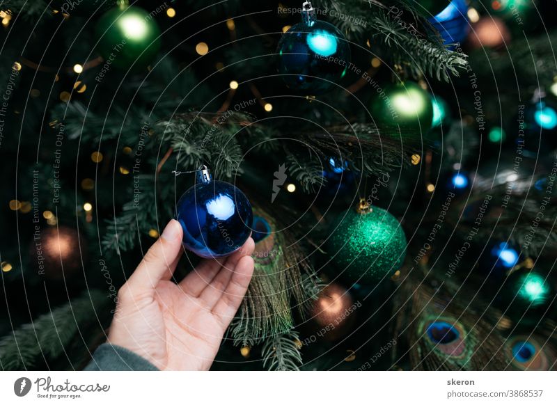 Christbaumschmuck: Weihnachtsschmuck, Lichterketten, die Dekoration in Form einer Pfauenfeder. Konzept: Inneneinrichtung für ein Wohnzimmer mit blauer Wand, Postkarte oder Plakat.
