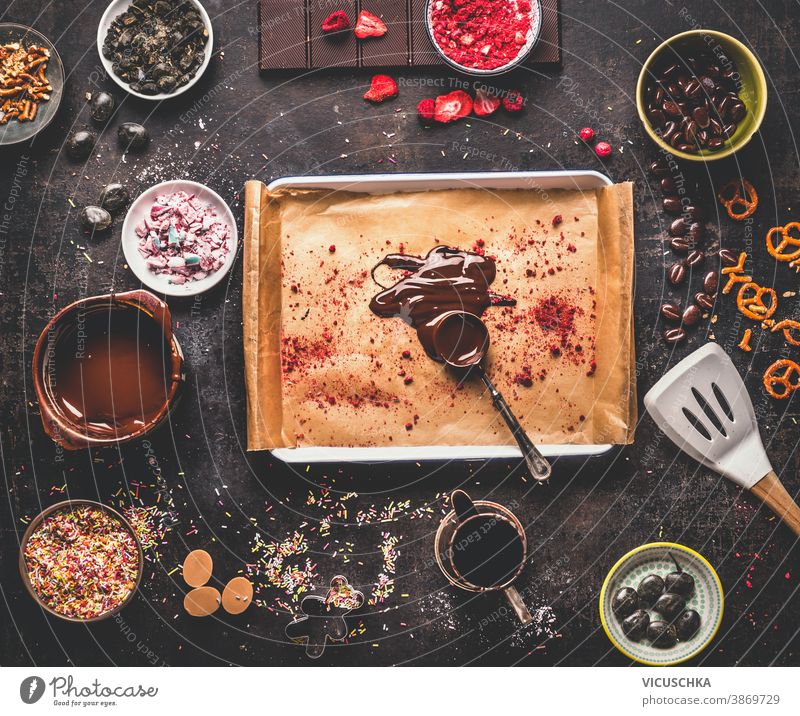 Löffel mit geschmolzener Schokolade auf rustikalem Küchentisch mit verschiedenen Bonbons und Süßigkeiten bar . Ansicht von oben Bar Draufsicht Tradition Raum