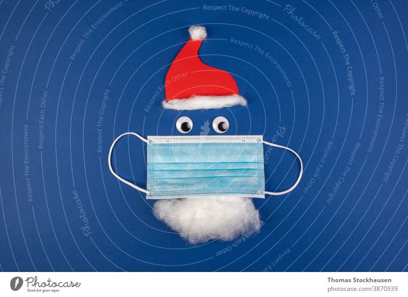 handgemachte Weihnachtsmann-Klausel mit Mottenschutz, Gesichtsmaske, roter Mütze und Bart, als Symbol für die Auswirkungen des Covid-Virus in der Weihnachtszeit