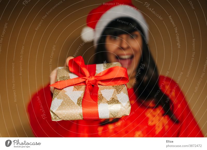 Frau mit Nikolausmütze überreicht freudig ein Weihnachtsgeschenk Weihnachten schenken Bescherung Freude euphorisch aufgeregt Weihnachten & Advent Geschenk