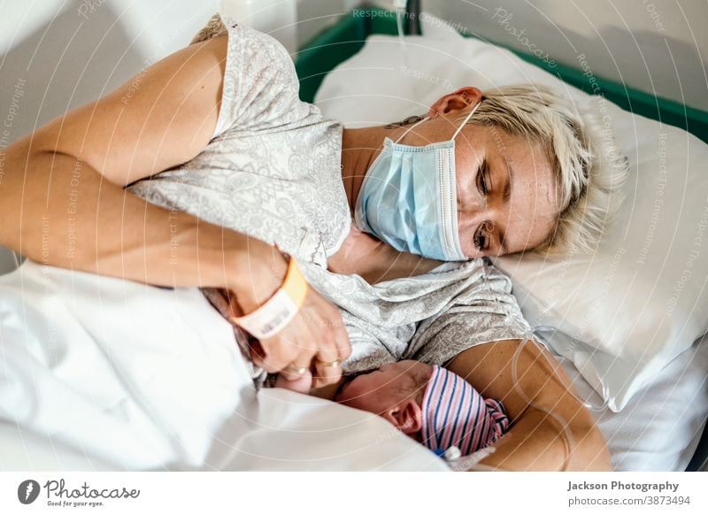 Eine neue Mutter stillt ihren neugeborenen Jungen während einer Pandemie maskiert Mundschutz Krankenpflege Baby Versand Krankenhaus Stillen Station Klinik