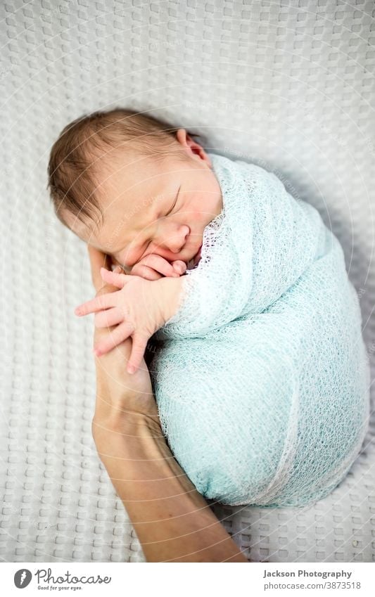 Lächelnder, in Blau gehüllter neugeborener Junge liegt auf der Hand der Mutter schlafendes Baby umhüllen bezaubernd Mama schön Schönheit Decke blau Born Pflege