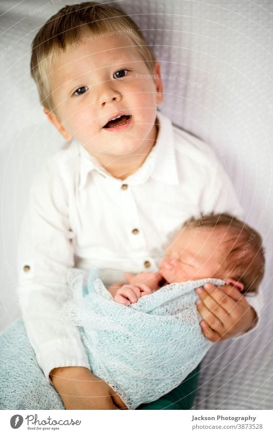 Drei Jahre alter Junge hält seinen neugeborenen Bruder Geschwister Familie Liebe Brüder Geschwisterkind umhüllen Kaukasier blond Gesicht Aussehen Lächeln