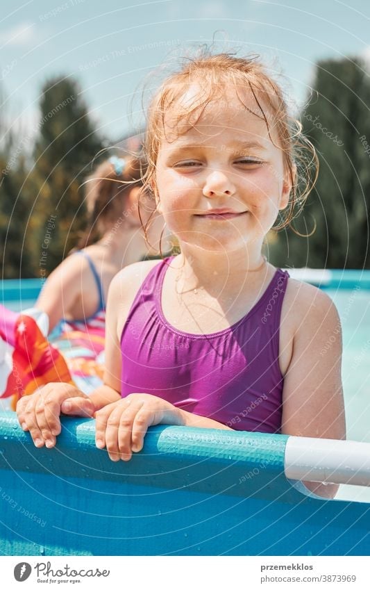 Porträt eines glücklich lächelnden Mädchens, das an einem sonnigen Sommertag in einem Schwimmbad steht und sich amüsiert authentisch Hinterhof Kindheit Kinder
