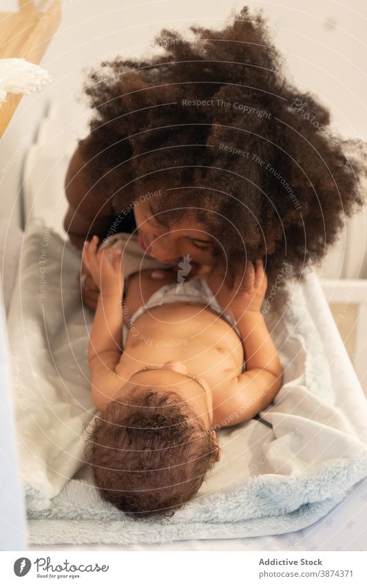 Schwarze Frau setzt auf Kleidung auf Baby Wandel & Veränderung Tisch Mutter angezogen Stoff Hose Pflege Kleinkind wenig ethnisch schwarz Afroamerikaner Lügen